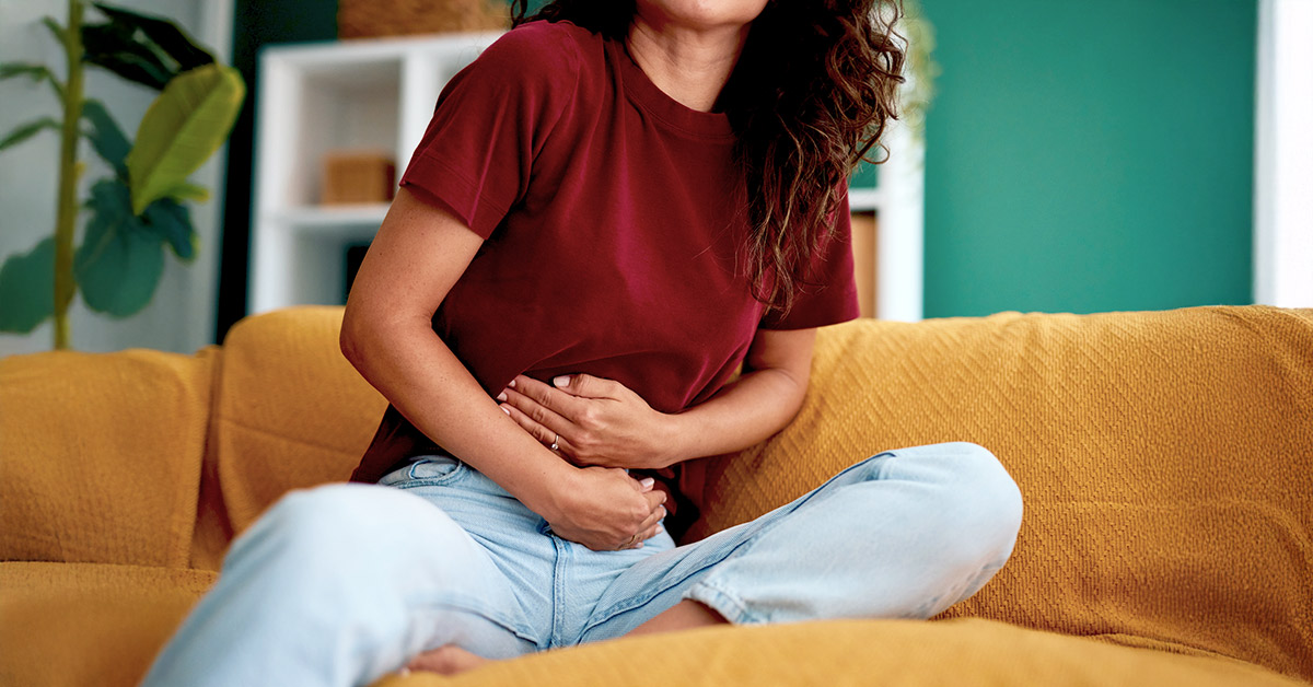 A woman in abdominal pain while sitting on the sofa at home