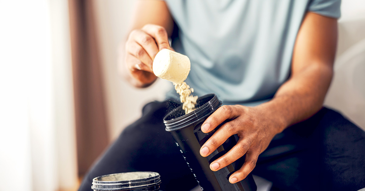 A man pouring creatine powder into a shaker