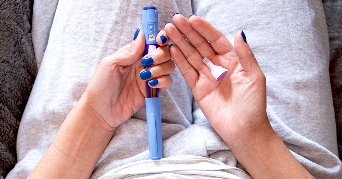 A woman holding GLP-1 injectible pen with cap