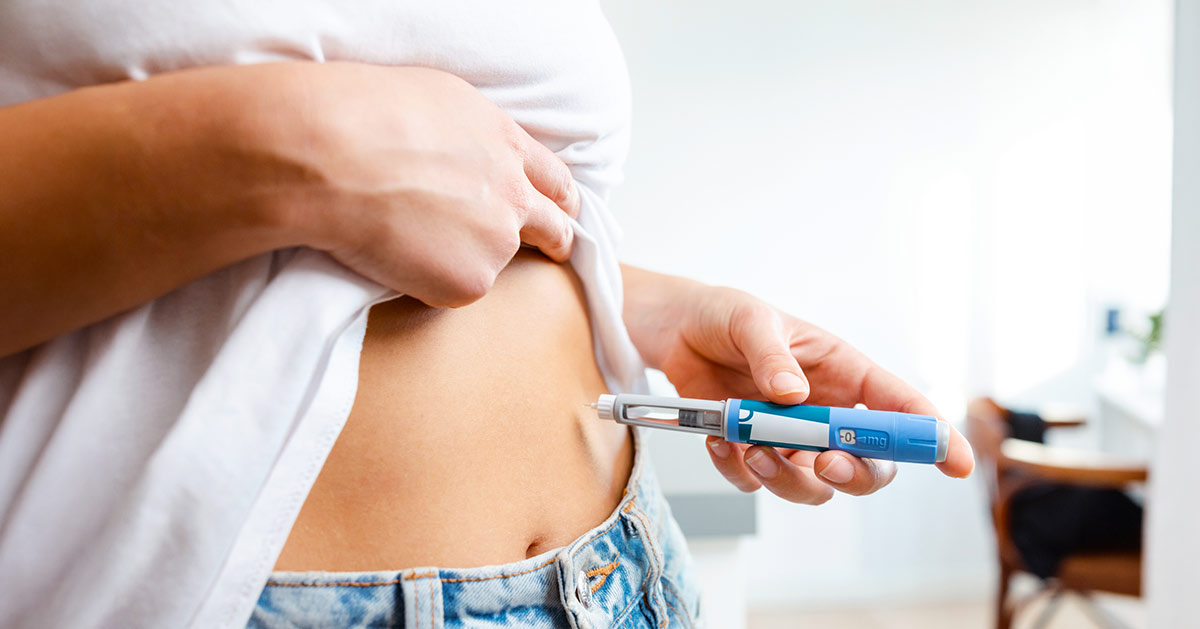 A woman self administering a GLP-1 injection into her stomach