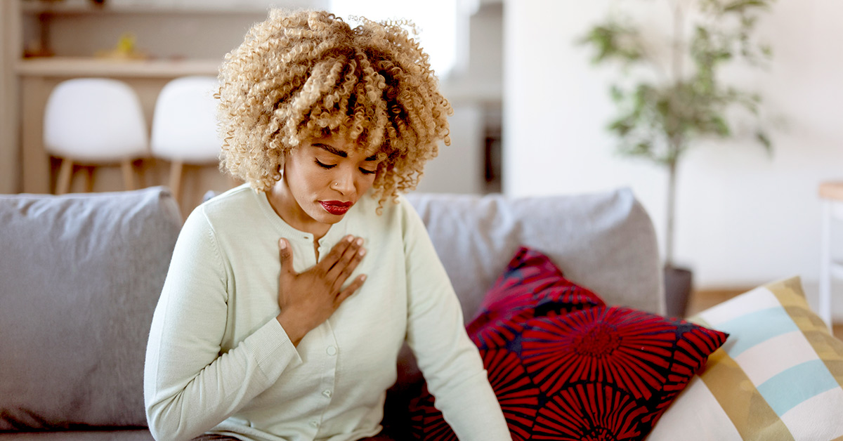 A woman experiencing heartburn with her hand placed on chest