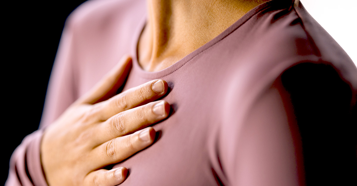 A woman places her hand on her chest, near the heart.