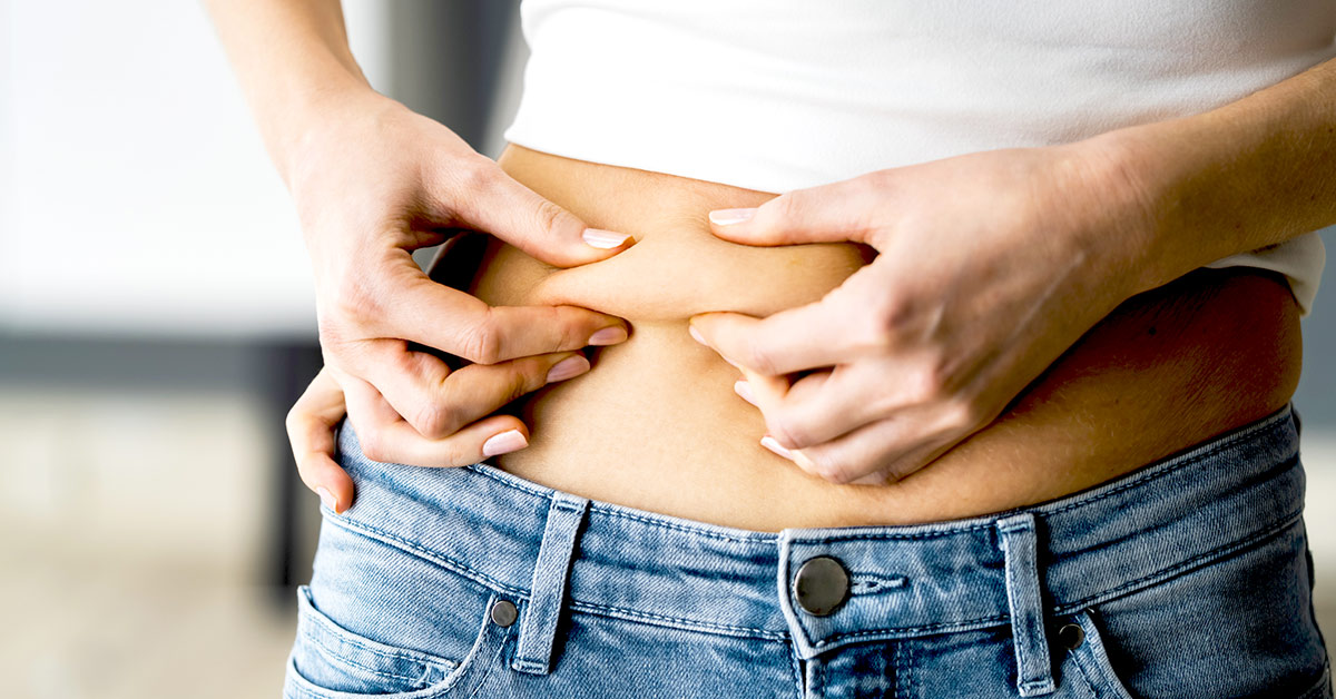 A woman punching her belly fat.