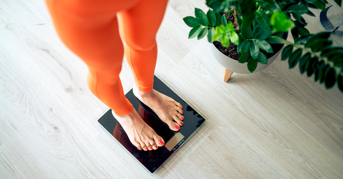 A woman in orange leggings standing weight scale