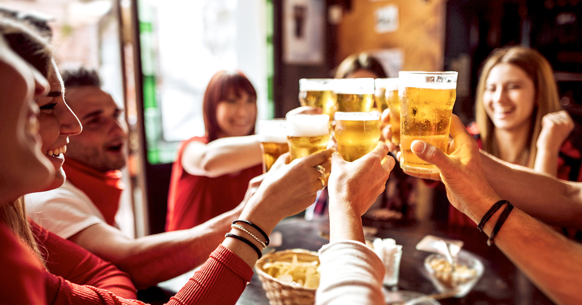 A group of friends doing a toast with beers at a bar.