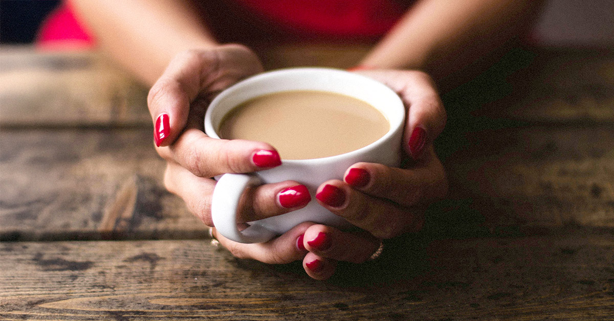 Woman holding a cup of coffee with both hands