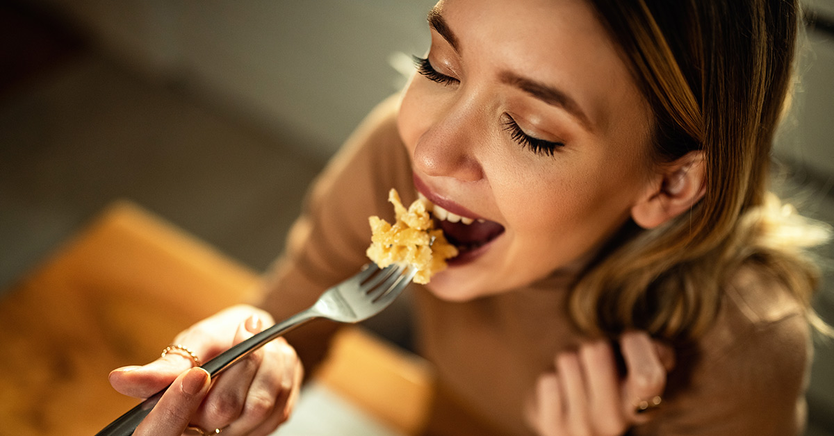 young woman eating and enjoying pasta