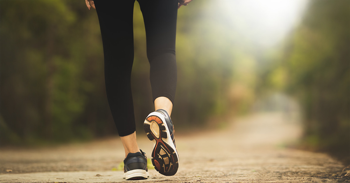 Woman walking down the trail in the wilderness with black shoes and leggings.