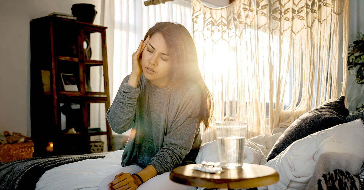 A dizzy young woman sitting down holding her head.