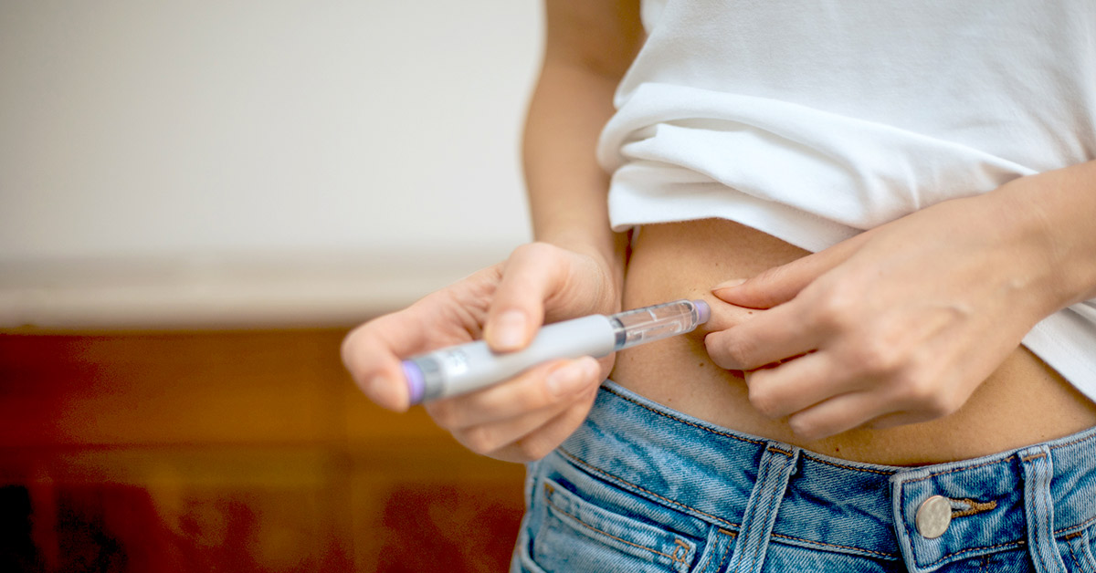 A woman self-administering a GLP-1 medication injection into her stomach
