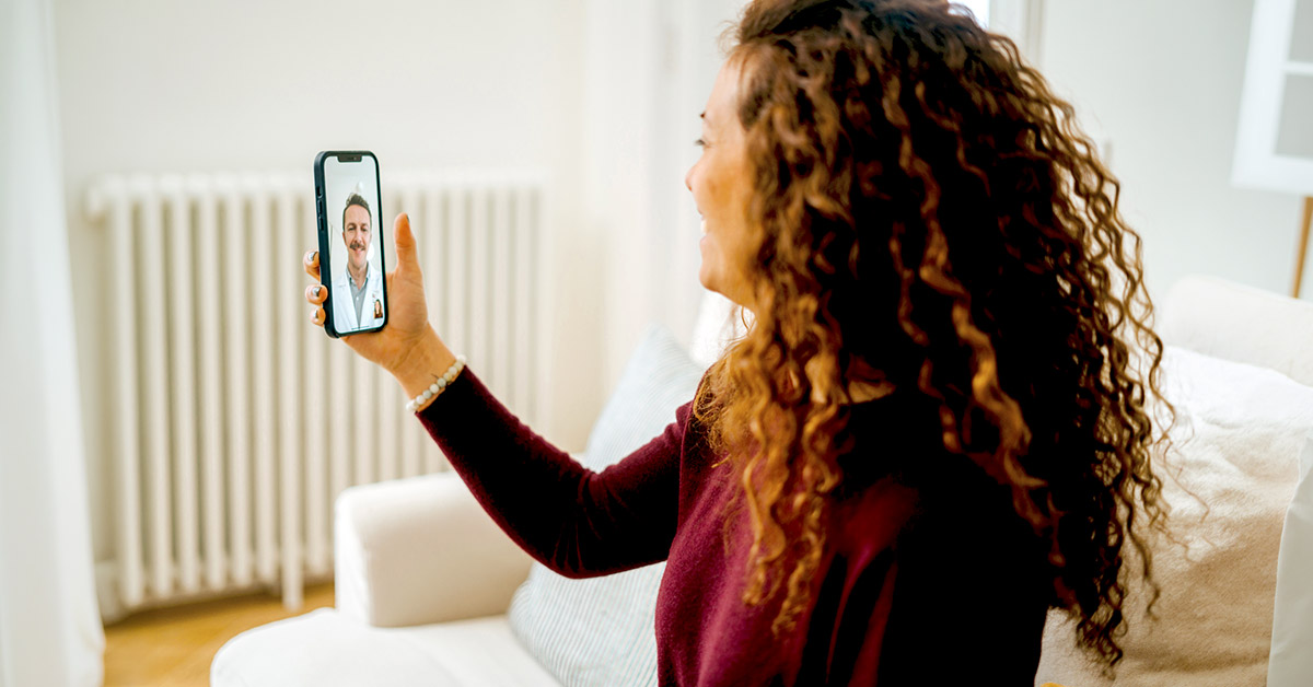 Woman having a video consultation at home with a healthcare provider on her smartphone.