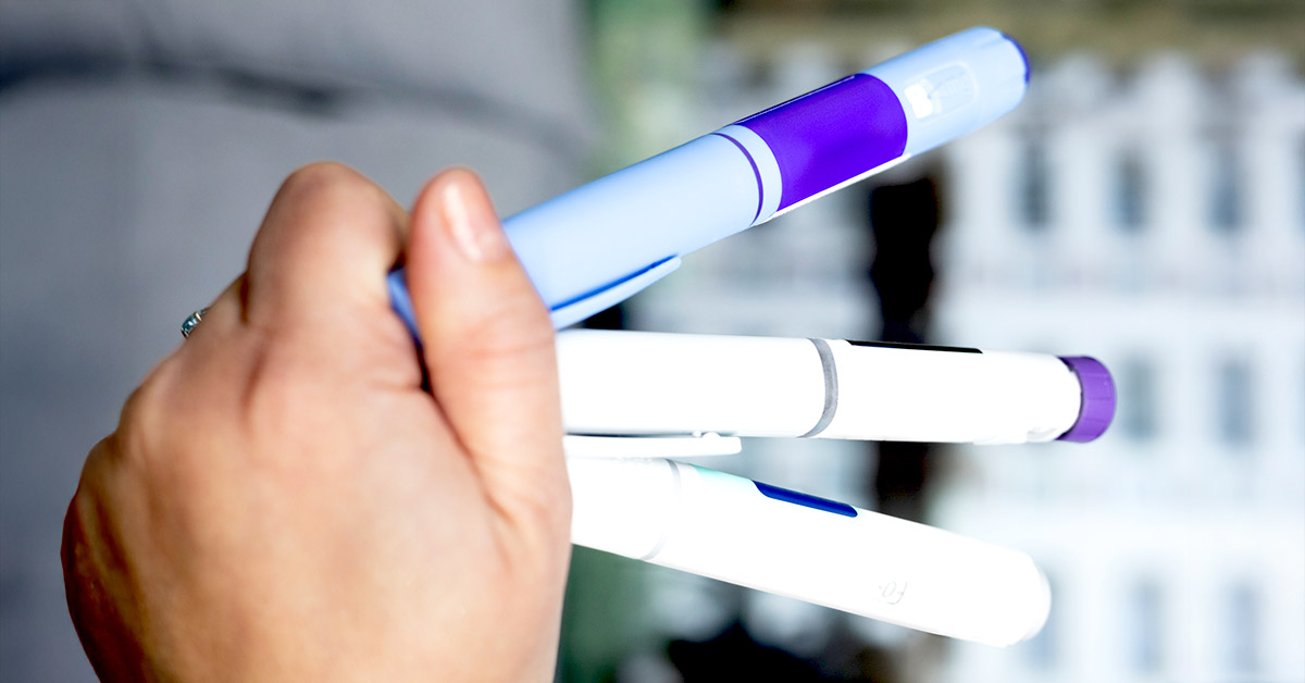 Woman holding three GLP-1 injectable pens in hand