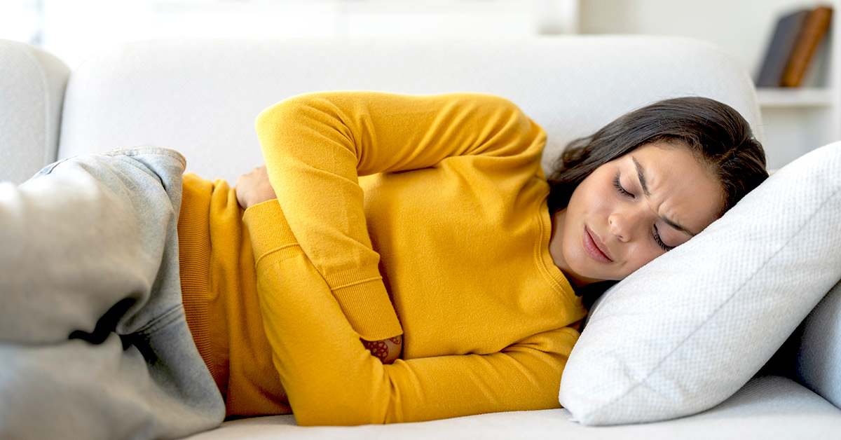 A woman lying down on couch with discomfort and nausea