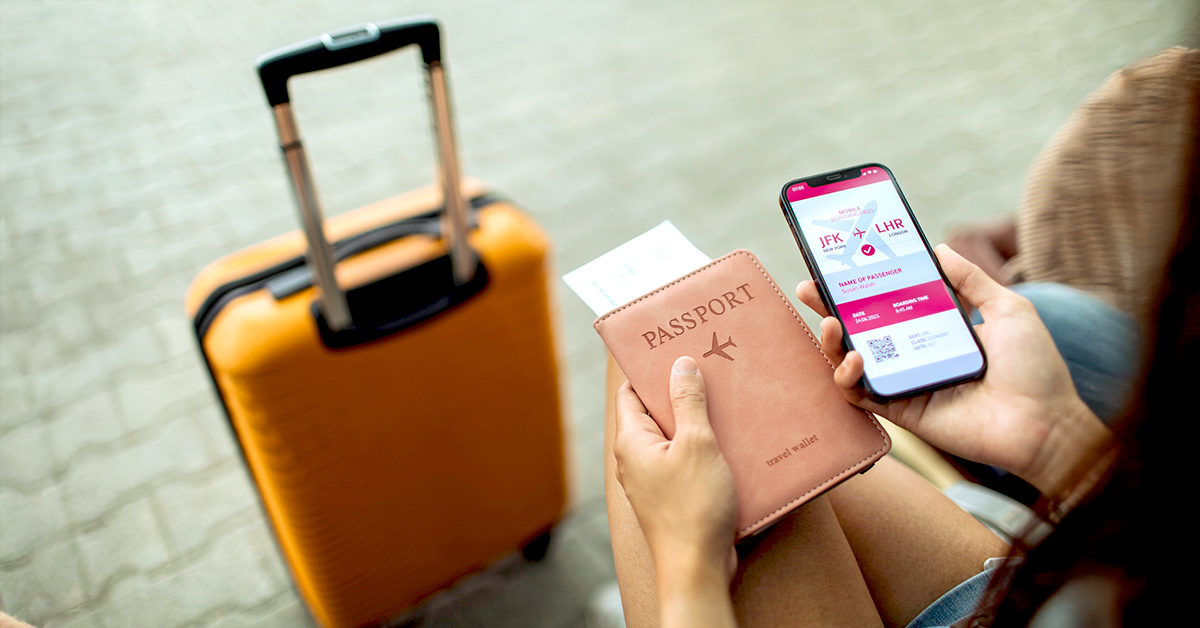 Woman sitting at the airport gate with luggage holding her electronic boarding pass and passport