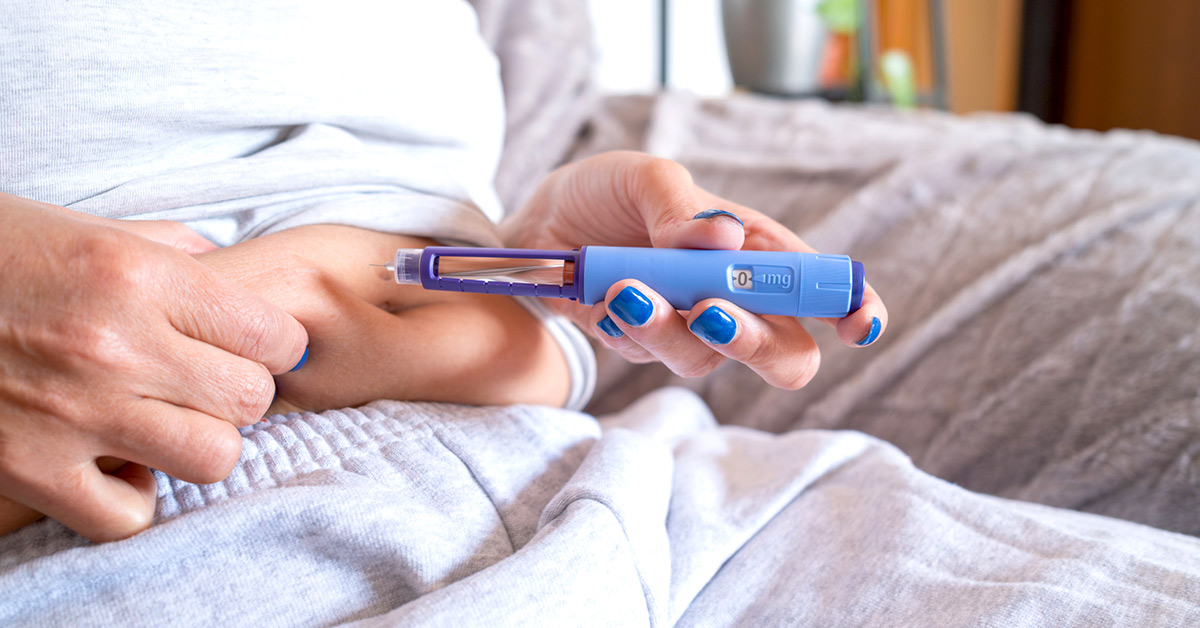 A woman self administering a glp-1 medication into her stomach.